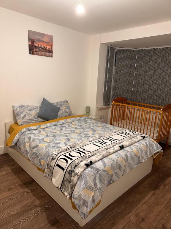 um quarto com uma cama com um edredão e uma janela em Lovely Hillingdon Family Holiday Home - 7 bedrooms em Ickenham