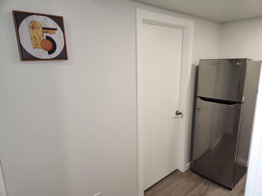 a kitchen with a refrigerator and a picture on the wall at A Modern & Homely 1 BR Suite in Winnipeg