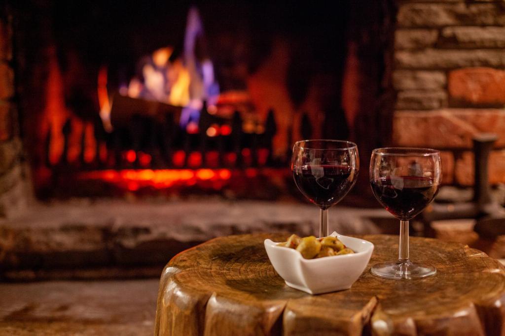 two glasses of wine and a bowl of food in front of a fireplace at BIESIADA in Korbielów