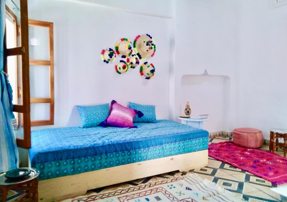 a bedroom with a bed with blue sheets and pink pillows at Apartamento en el corazón de la Medina in Tetouan