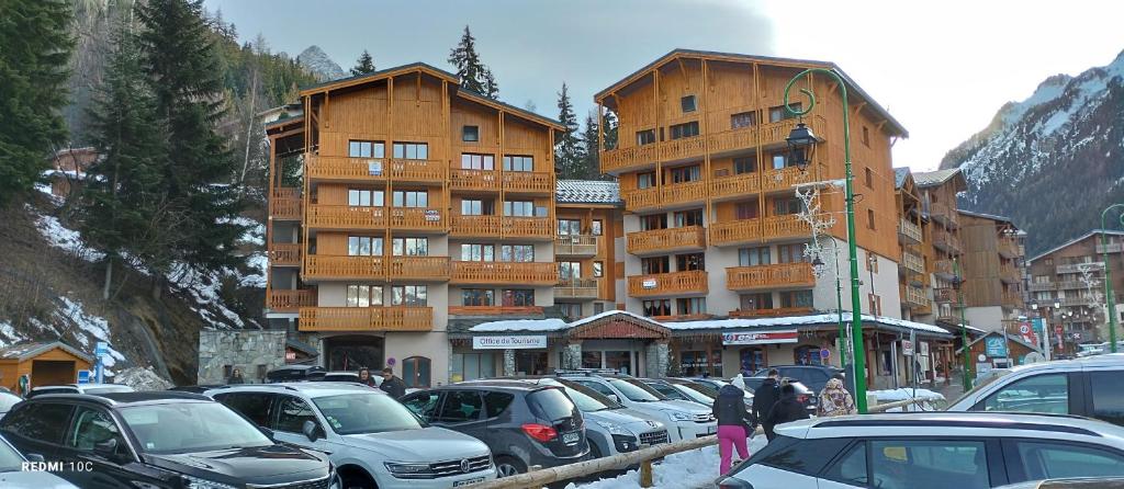 un parking avec des voitures garées devant un bâtiment dans l'établissement Appartement Valfrejus Les Melezets1 21m2 centre station, à Modane