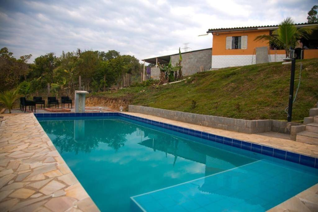 een blauw zwembad met een huis op de achtergrond bij Sitio 2k Mairinque in Mairinque