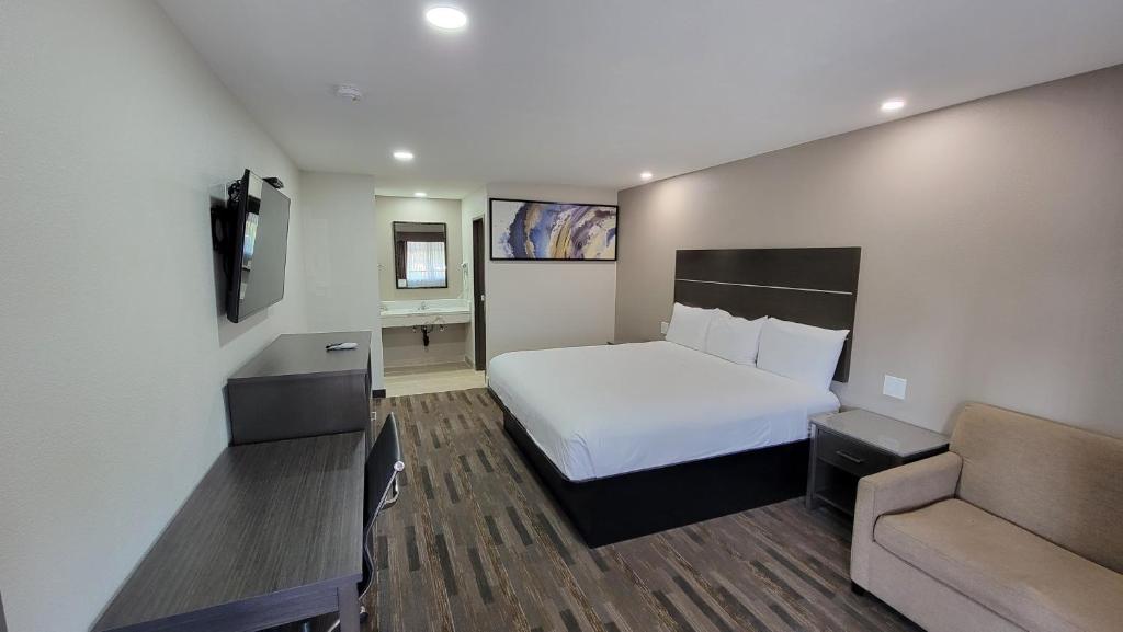 a hotel room with a bed and a couch at Travelodge by Wyndham Buena Park in Buena Park