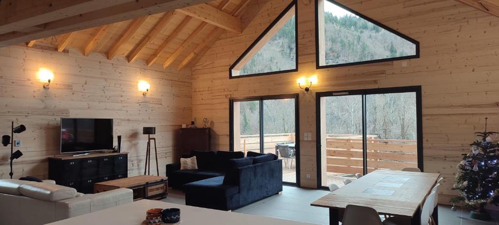 a living room with a couch and a tv and windows at La Tour de l'Enversin in Vaujany