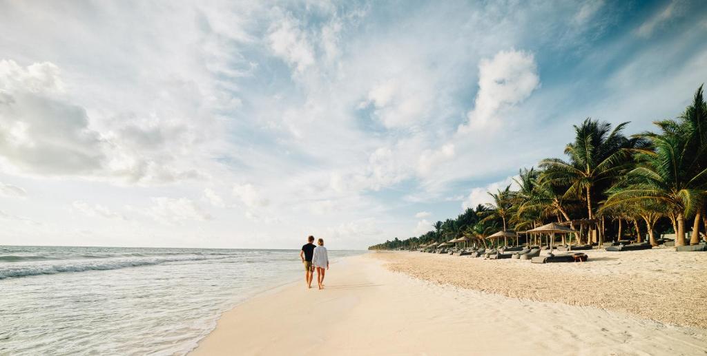 Una pareja caminando por la playa en Nomade Tulum en Tulum