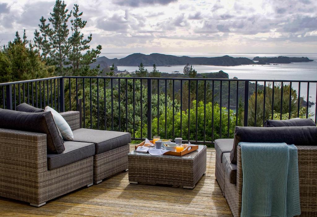 balcón con muebles de mimbre y vistas al agua en The Retreat - Luxury Hillside villa at Te Ngaere Bay en Kaeo