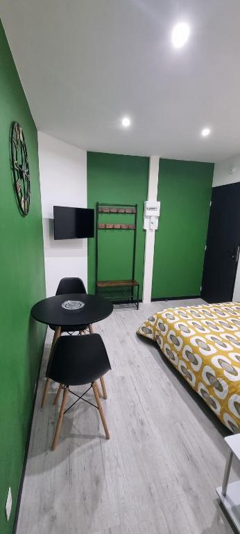 a bedroom with a bed and two chairs and a table at Studio Aloe tout confort rénové in Saint-Quentin
