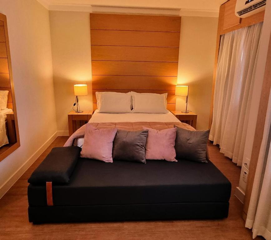 um quarto com uma cama com um repousa-pés preto em Linda suite em hotel ao lado do aeroporto de Congonhas em São Paulo