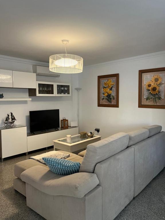 ein Wohnzimmer mit einem Sofa und einem TV in der Unterkunft Apartamento Reyes La Carihuela in Torremolinos