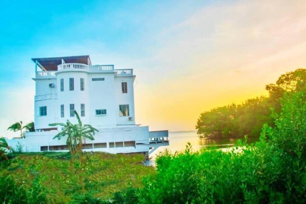 See Belize SUNRISE Sea View Studio with Infinity Pool & Overwater Deck في مدينة بليز: مبنى أبيض على جانب النهر