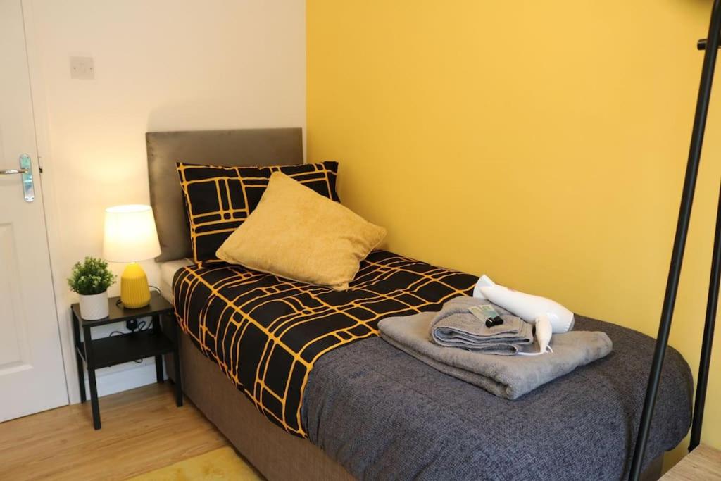 a bedroom with a bed with a yellow wall at Elegant room in stylish house in Milton Keynes