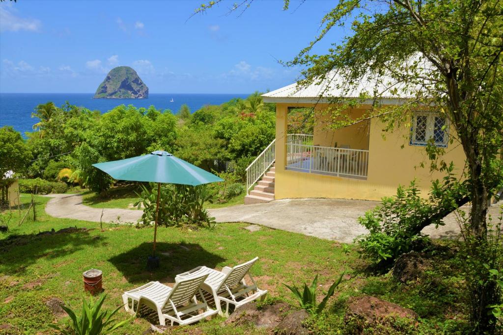 a house with two chairs and an umbrella at Résidence les Océanides in Le Diamant