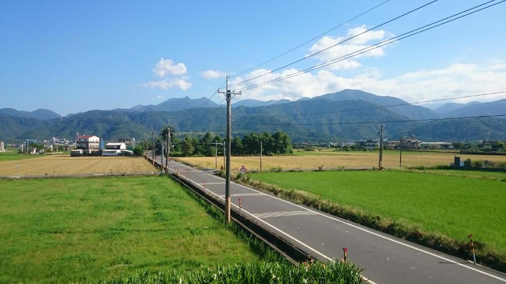an empty road in a field with mountains in the background at Yilan Real Fun Homestay in Dongshan