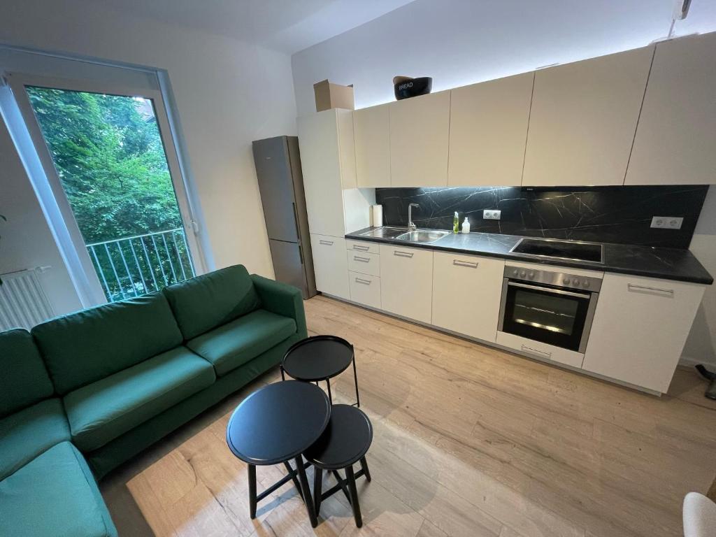 a living room with a green couch and a kitchen at City Apartment Messe Graz Amélie in Graz