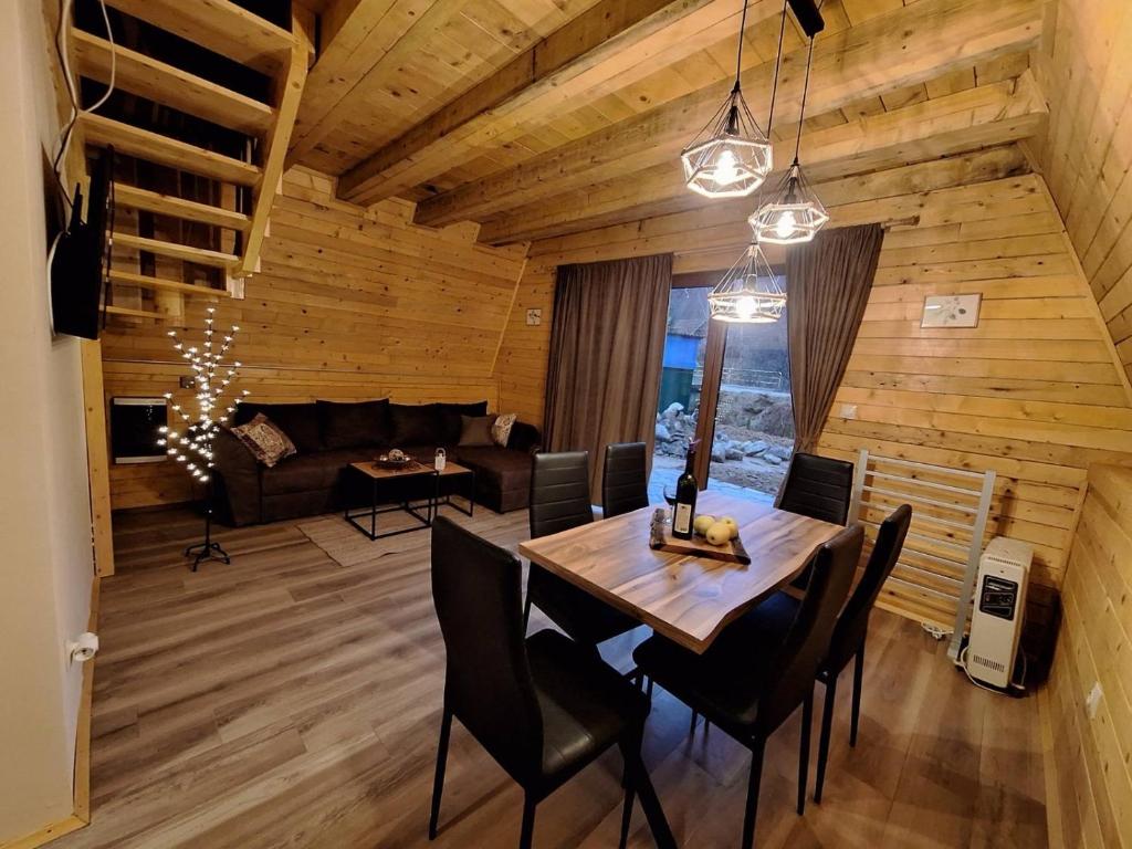 a dining room and living room with a table and chairs at Brvnare Todorovic in Crni Vrh