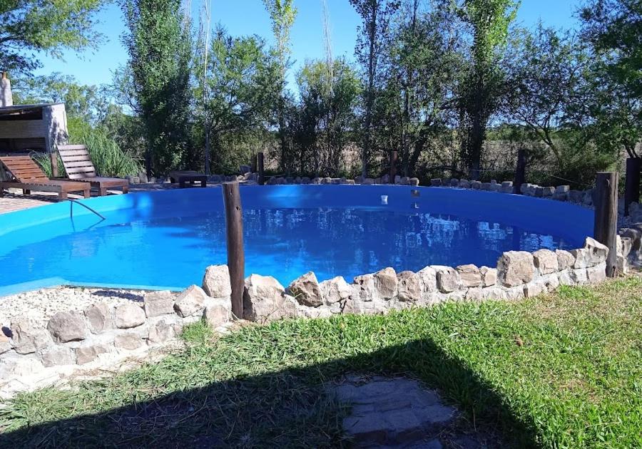 a large blue swimming pool with a stone wall around it at Valdemoro Hosteria in Gualeguaychú