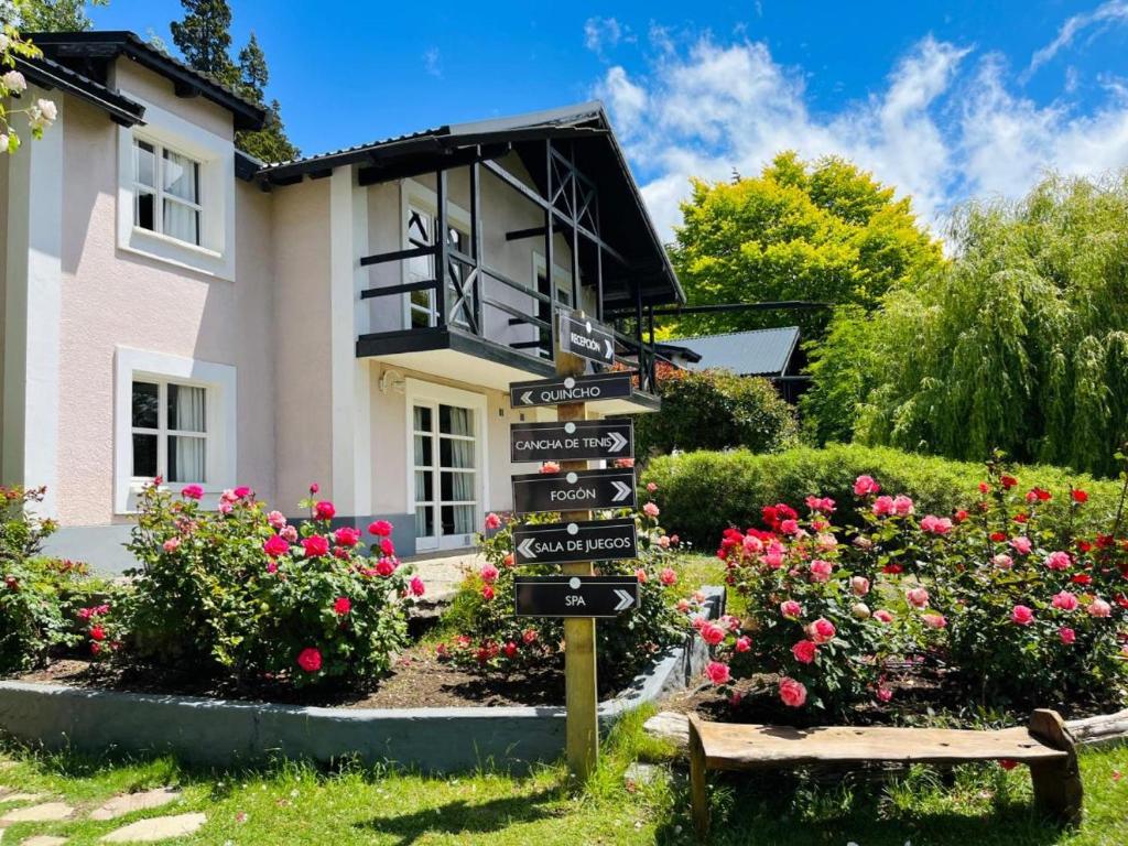 AldeaAndina Tiempo Compartido Hotel&Spa Bariloche في سان كارلوس دي باريلوتشي: علامة أمام منزل به زهور