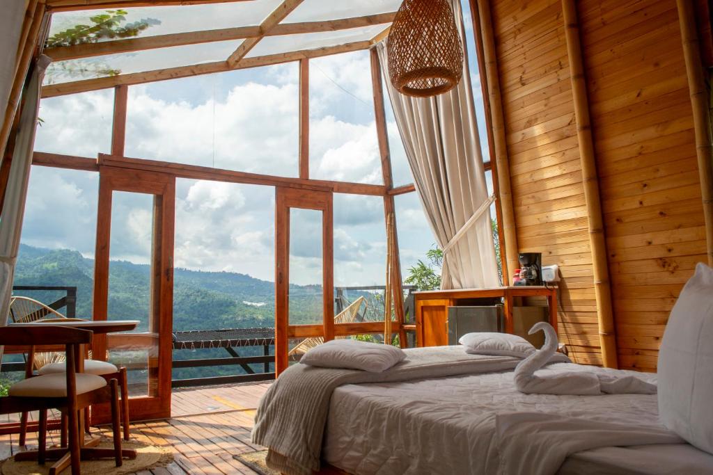 um quarto com uma cama e uma grande janela em NaturalMente Glamping em San Antonio del Tequendama