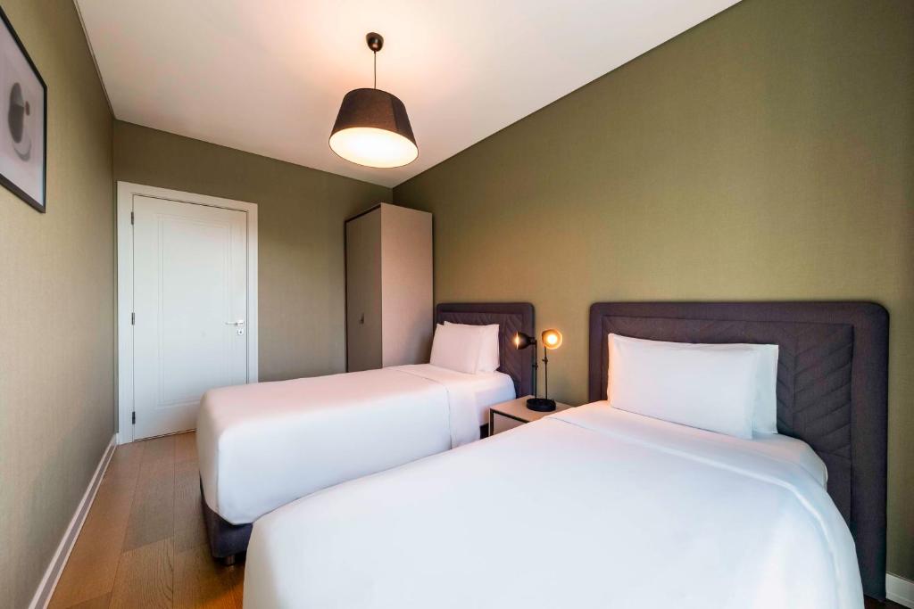 two beds in a room with two white beds at Radisson Residences Vadistanbul in Istanbul
