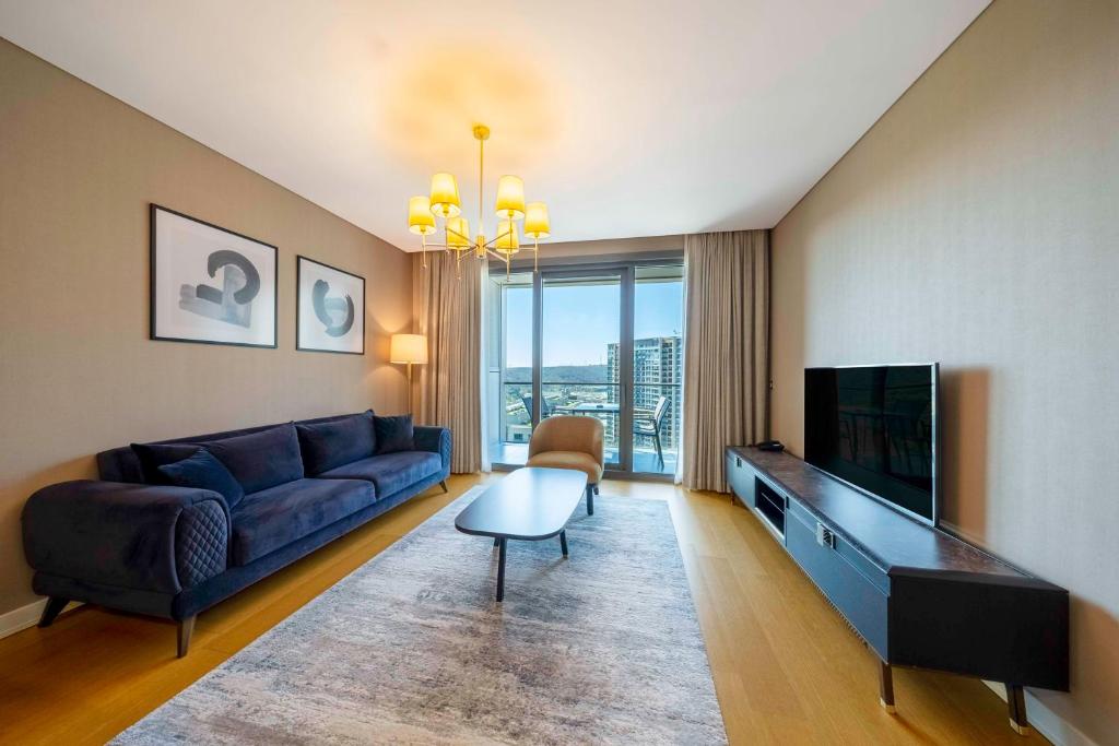 uma sala de estar com um sofá azul e uma televisão em Radisson Residences Vadistanbul em Istambul