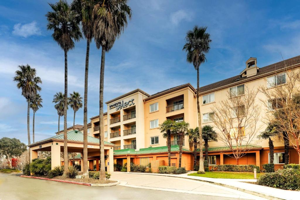 a hotel with palm trees in front of it at Sonesta Select San Francisco Airport Oyster Point Waterfront in South San Francisco