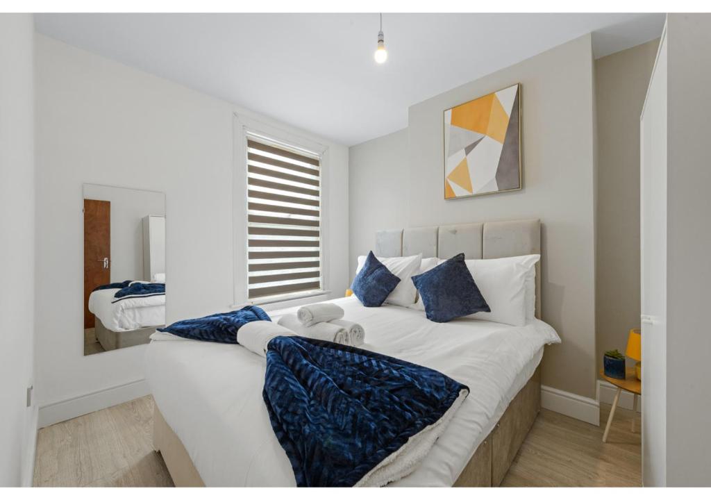 ein weißes Schlafzimmer mit einem großen Bett mit blauen Kissen in der Unterkunft Serenity, Scenery, Shopping, & Sports in London