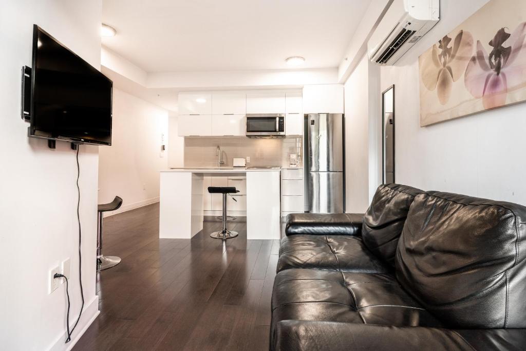 a living room with a leather couch and a kitchen at One bedroom apartment - 507 in Montreal