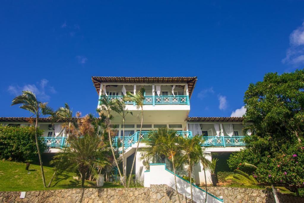 a building on the beach with palm trees at Pousada Aroma do Mar by Latitud Hoteles in Búzios