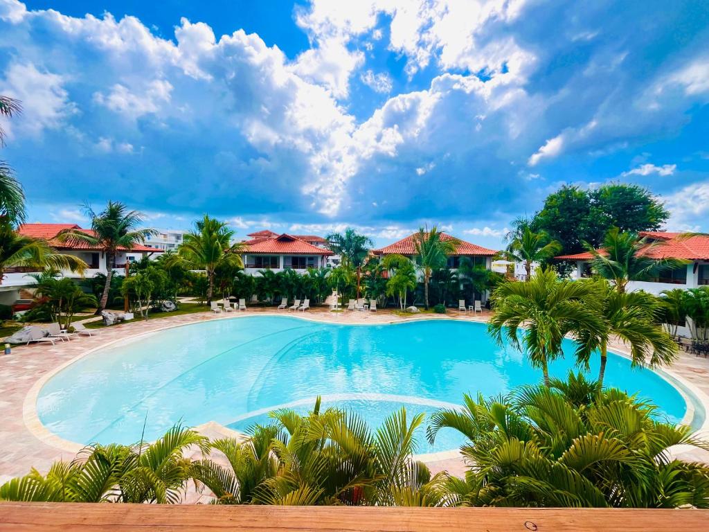 - une piscine dans un complexe avec des palmiers et des maisons dans l'établissement Paraíso Bayahibe, à Bayahibe