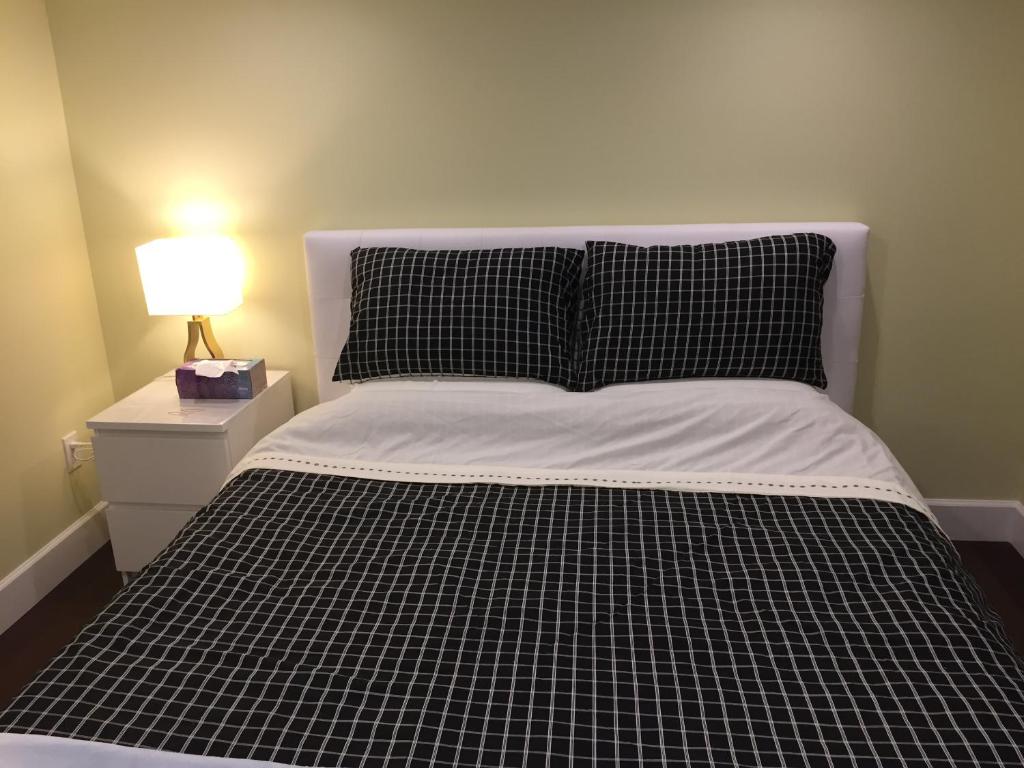 a bed with a black and white comforter and a lamp at Arbutus Rose House at Vancouver west side in Vancouver
