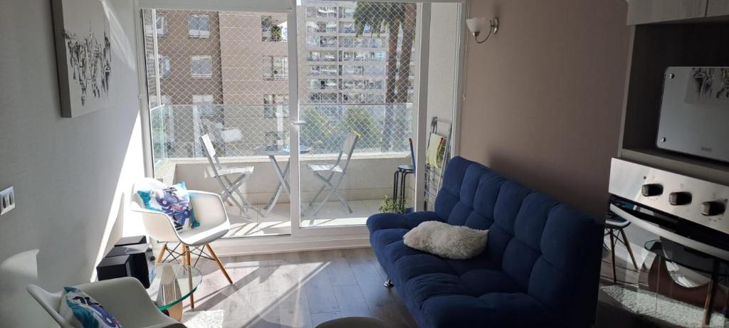 een woonkamer met een blauwe bank en een raam bij Depto. en el centro de Viña in Viña del Mar