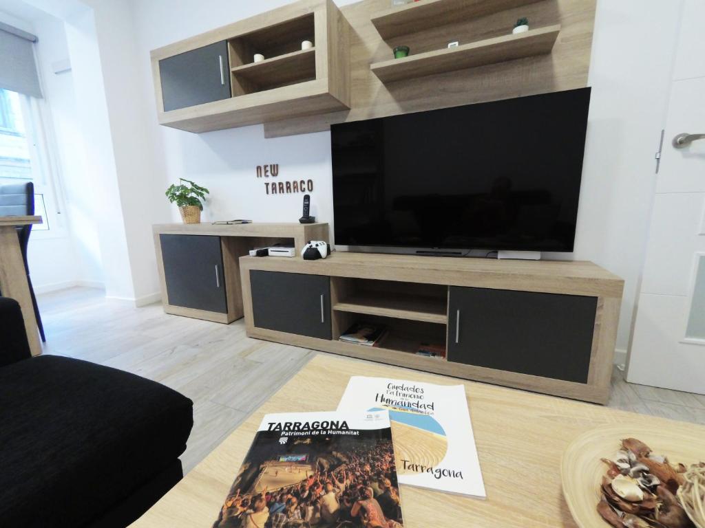 a living room with a television and a book on the floor at Apartamento New Tarraco in Tarragona