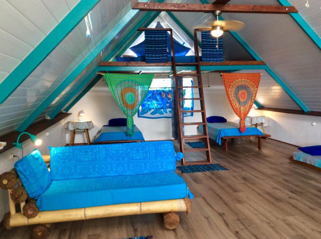 a living room with a blue couch and a loft at L'Auberge de Tahiti Iti - Beach hostel in Afaahiti