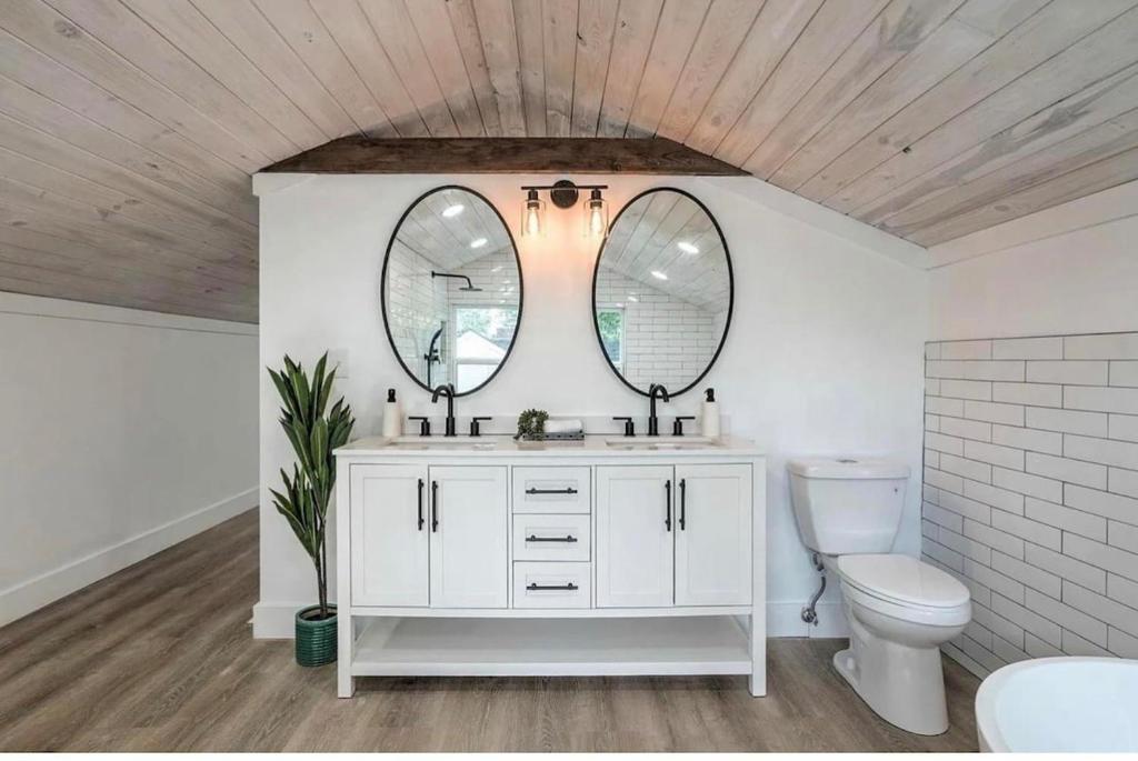 uma casa de banho com um lavatório, um WC e 2 espelhos em Midtown Masterpiece Whot Tub, Pets Welcome! em Tulsa
