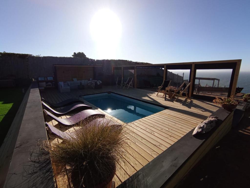 a swimming pool on a wooden deck with two chairs at Hotel Casa Puccllana in Constitución
