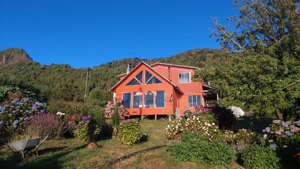 a house in the middle of a garden with flowers at Cabaña Frente Al mar, Carretera Austral km 38,6, Puerto Montt in Puerto Montt