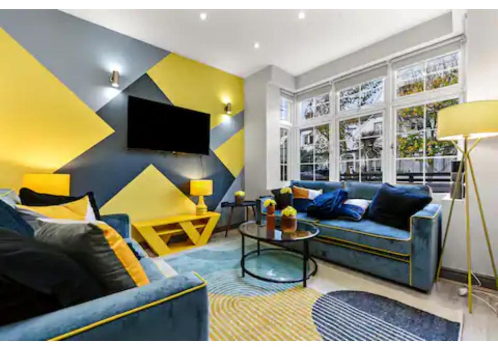 a living room with a blue couch and a tv at Three Bedroom Home - Perfect for Large Groups in London