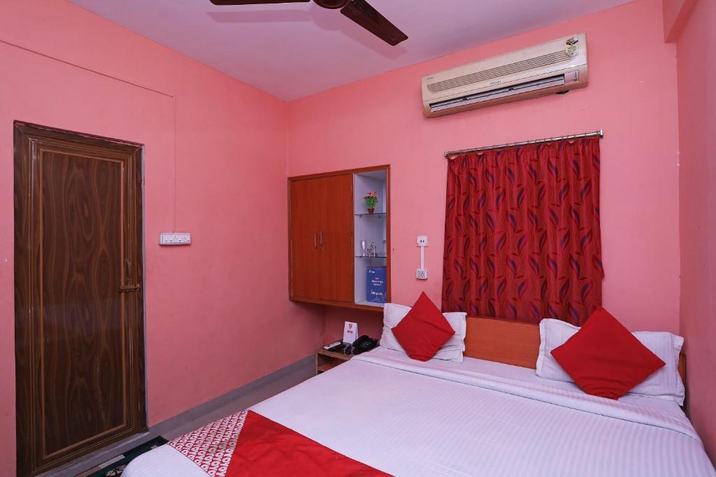 a bedroom with pink walls and a bed with red pillows at OYO Silver Inn Near Acropolis Mall in Jādabpur