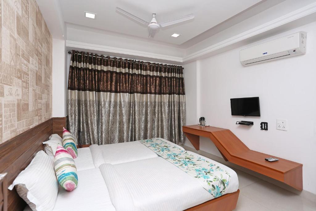 a bedroom with a bed and a desk and a window at OYO Hotel Grand Nishat in Patna
