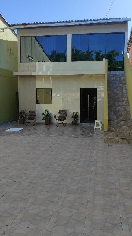 - un grand bâtiment avec une terrasse dotée de chaises dans l'établissement Suites Mar Azul, à São José da Coroa Grande