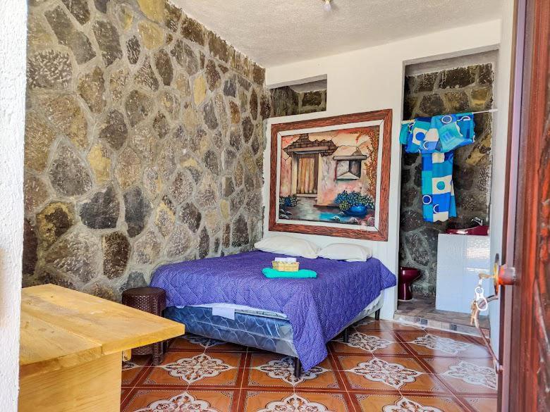 a bedroom with a purple bed in a stone wall at Casa Don Clemente in San Pedro La Laguna