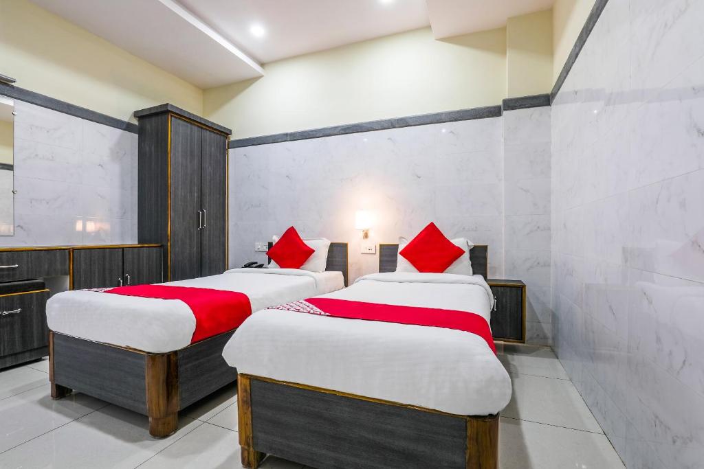 two beds with red pillows in a room at Hotel Src Grand in Vijayawāda