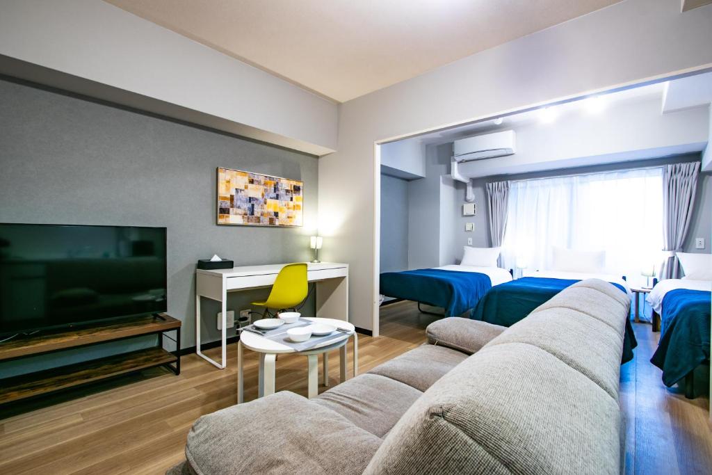 een woonkamer met een bank en een flatscreen-tv bij Minn Juso in Osaka