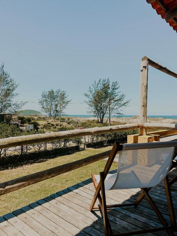 a chair sitting on a deck with the ocean in the background at Kahuma in Imbituba