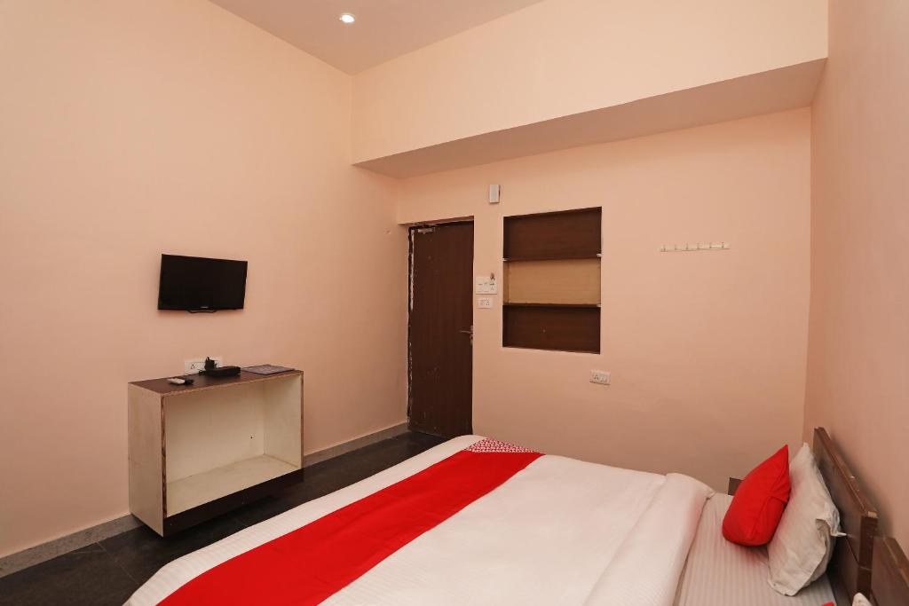 a bedroom with a bed and a tv on the wall at OYO Hotel Emerald in Raipur