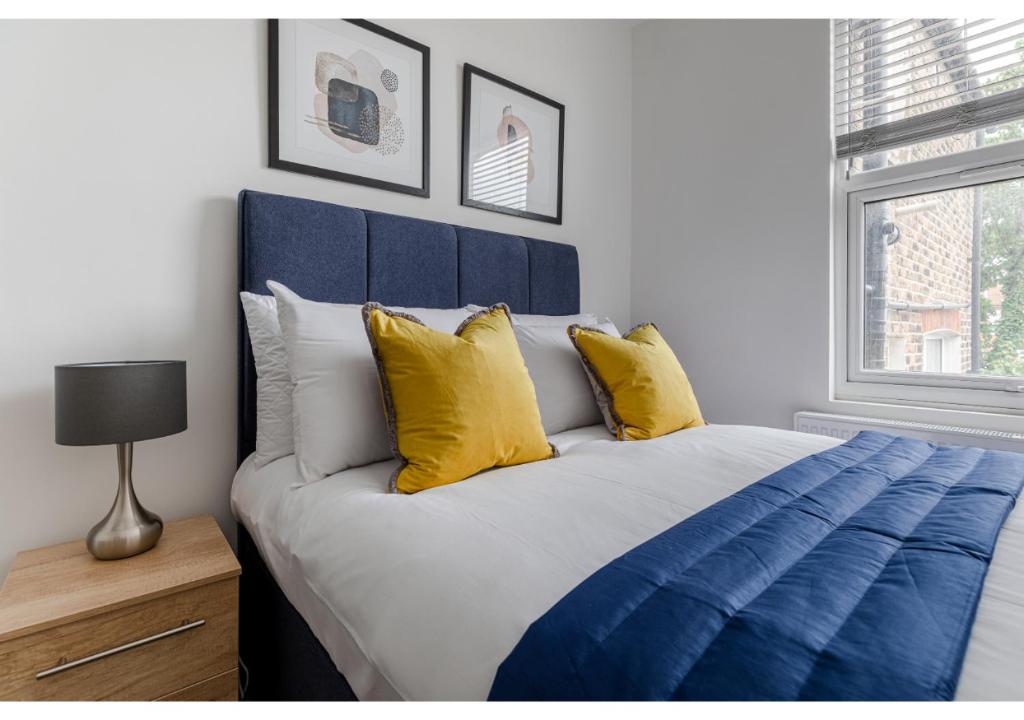 a bedroom with a blue and white bed with yellow pillows at Simply Perfect 2BR 2BT Apartment in London