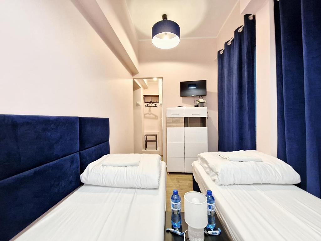 2 łóżka w pokoju z niebieskimi zasłonami w obiekcie Hostel Helvetia - PRIVATE ROOMS in CITY CENTER and OLD TOWN w Warszawie