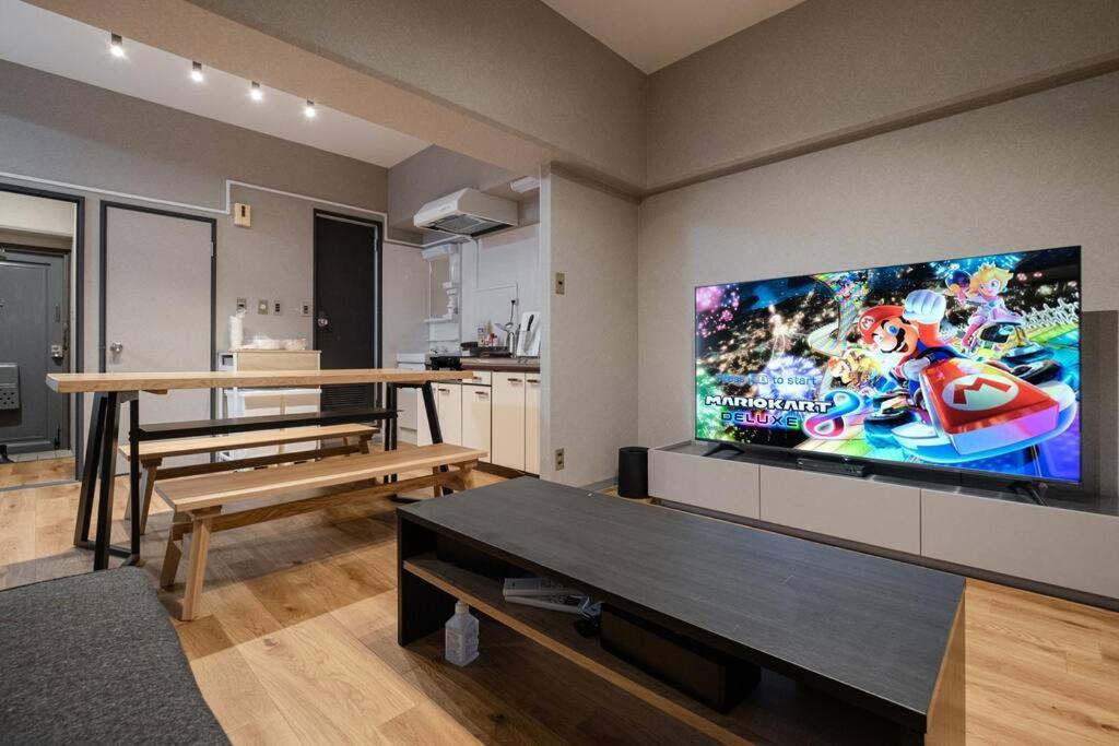 a living room with a large flat screen tv on the wall at TasoneUrbanStayOsaka なんば日本橋南不夜城706 in Osaka