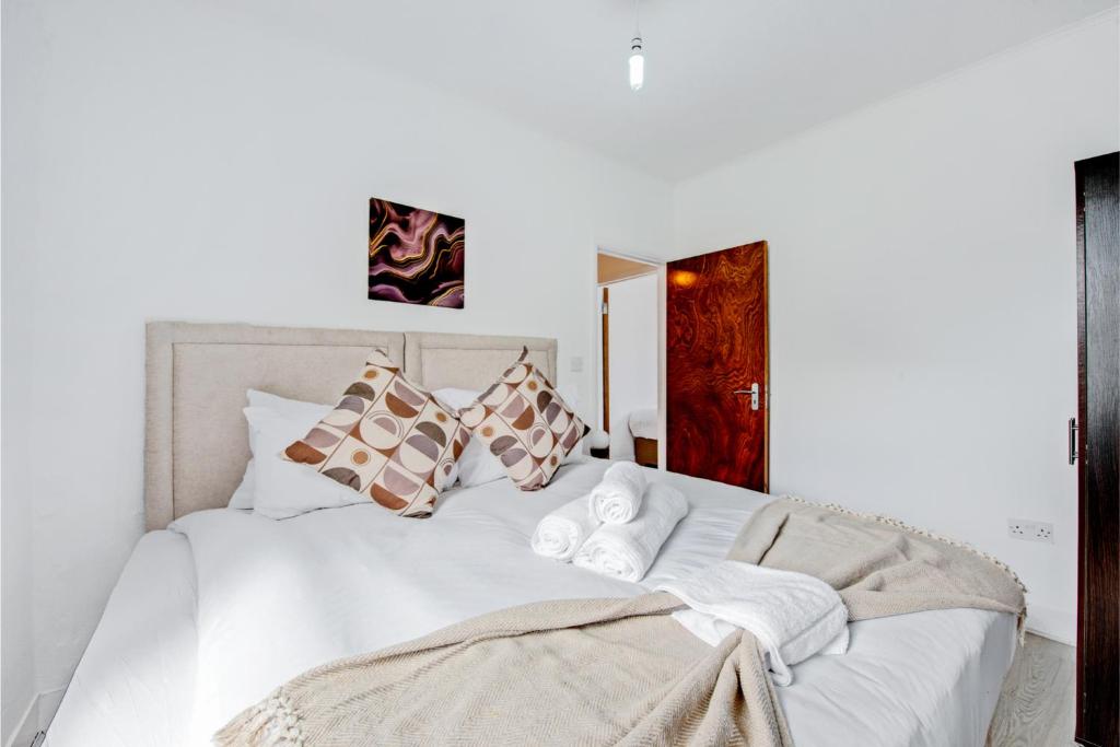 un letto bianco con cuscini e asciugamani di Lovely Home - Park Views & Ideal Transport Links a Londra