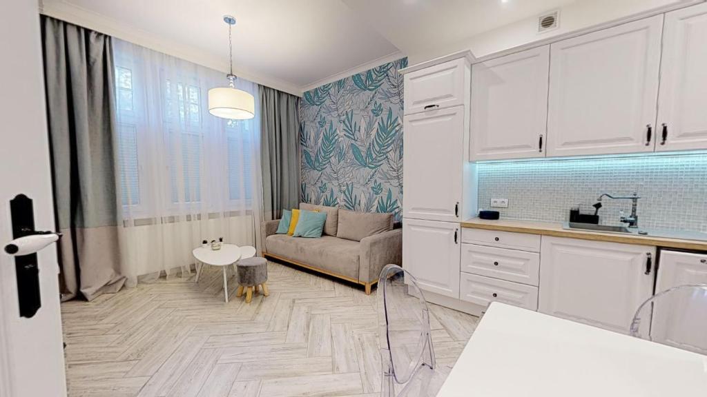 eine Küche und ein Wohnzimmer mit einem Sofa und einem Tisch in der Unterkunft Lillu Apartament 2 in Bydgoszcz
